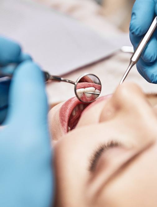 Close-up of patient having teeth examined by dentist