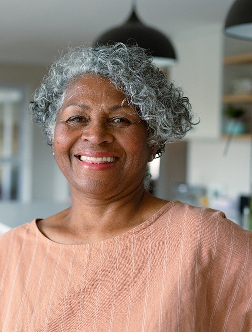 Senior woman in pink shirt smiling in kitchen