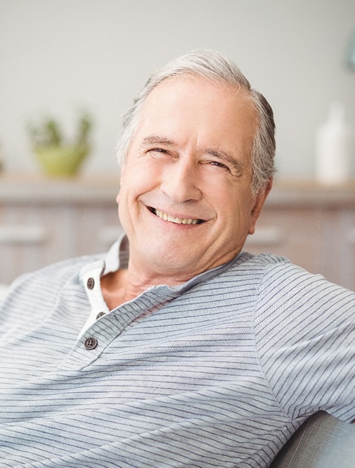 Senior man in striped shirt sitting on couch